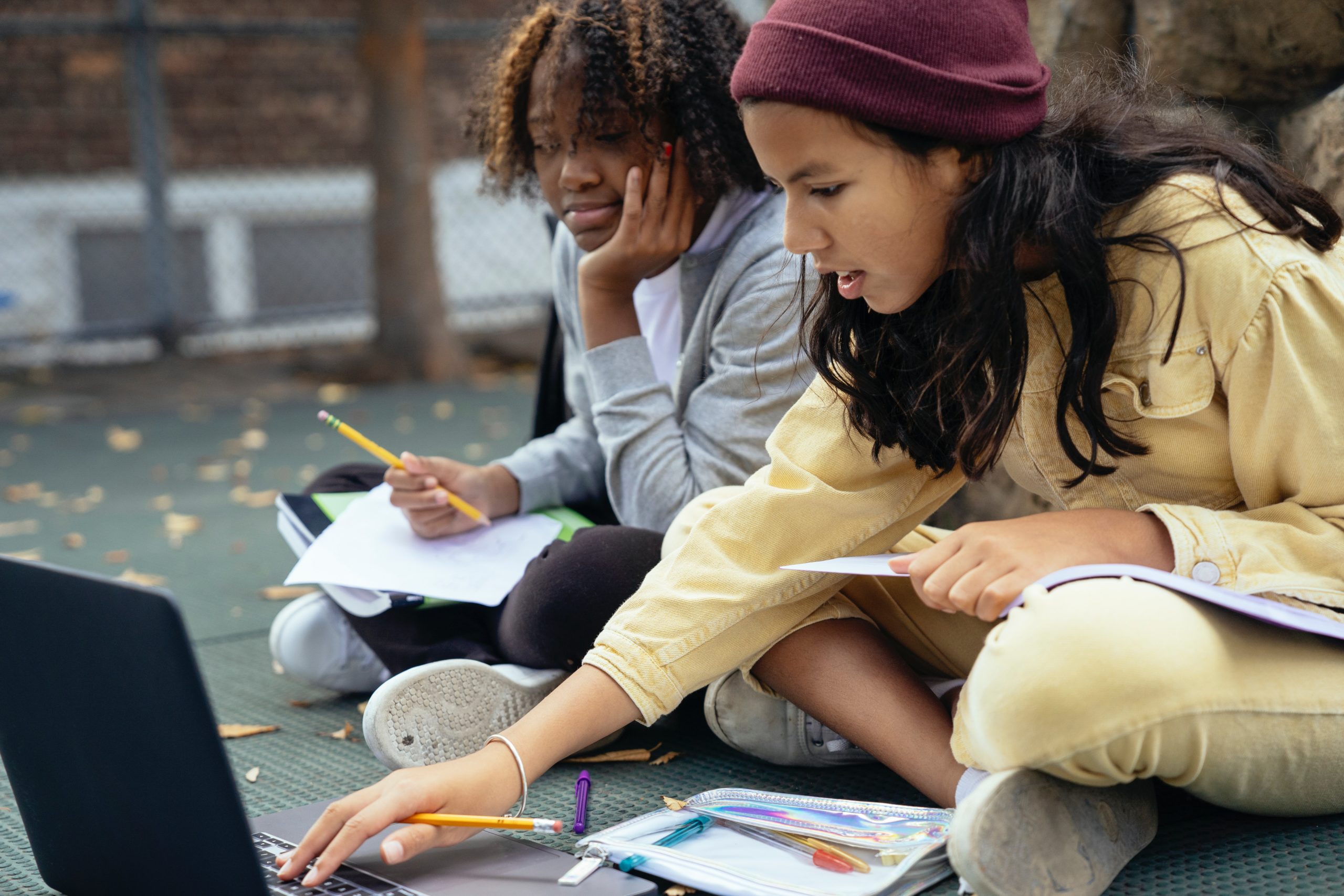 Two young students working together on an assignment outdoors.